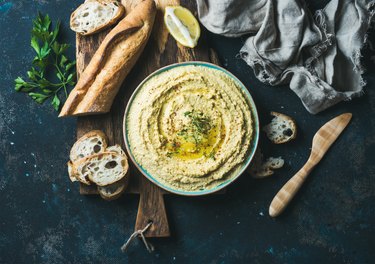 Homemade hummus with lemon, herbs and freshly baked baguette