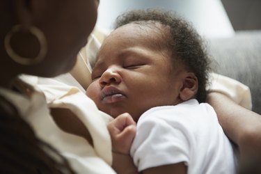 Black mother holding sleeping baby son