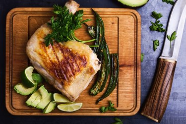 Grilled chicken leg and green vegetables on cutting board