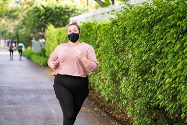 一名戴着运动面罩的女子在人行道上跑步