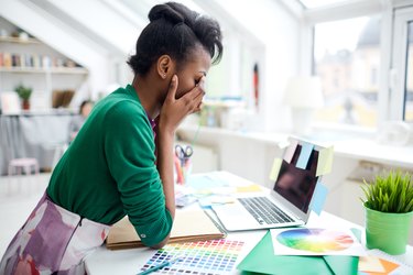 A woman sitting at her desk who is stressed from working too much