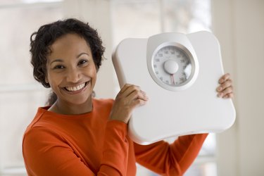 Happy Black woman holding scale