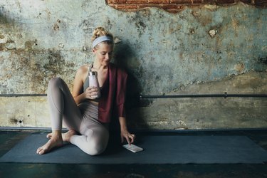 Woman in yoga clothes looking at fitness social media accounts on smart phone