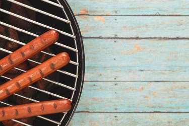 Three Hotdogs Grilling on Rustic Blue Picnic Table