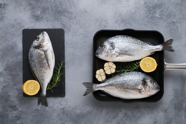 Three Fresh raw sea bream fish (dorado) on gray background. Healthy food concept. Top view, copy space