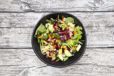 Bowl of autumnal salad with lettuce, carrots, avocado, beetroot, pumpkin and sunflower seeds, pomegranate and quinoa