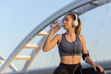 女子在户外跑步后喝水