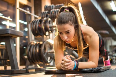 Sporty woman doing plank exercise in gym.