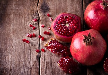 Some red pomegranates with seeds on old wooden table