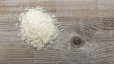 uncooked long grain rice on a wooden background.