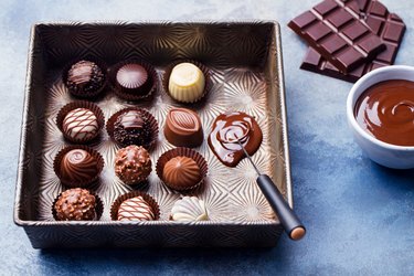 Chocolate candies in a vintage baking dish with chocolatier tool. Close up.