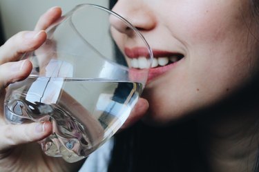 Close-Up Midsection Of Young Woman Drinking Water At Home