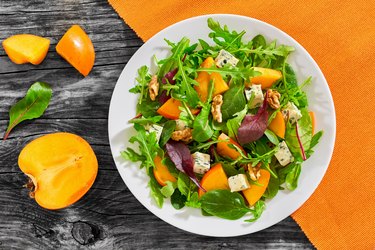 salad with persimmon slices, mix of lettuce leaves, blue cheese