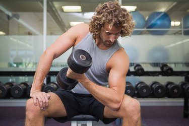 Young man exercising with dumbbell in gym