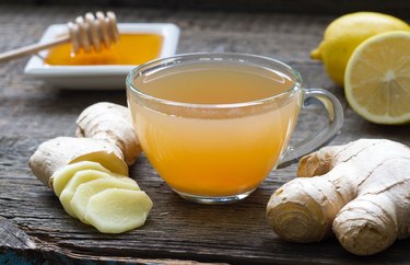 Ginger homemade tea infusion on wooden board with lemon, as an example of what to drink after hangover