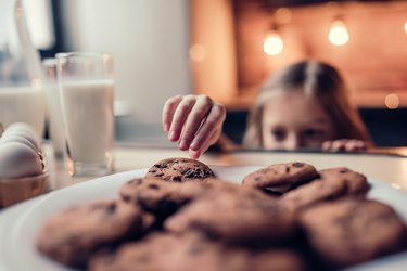 Little girl grabbing cookies in kitchen