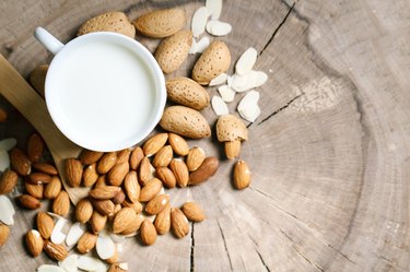 Almond and almond milk on a wooden table in the summer garden. Useful food