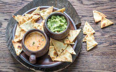 Bowls of guacamole and queso with tortilla chips.