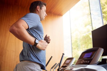 Man Exercising On Treadmill At Home Wearing Smart Watch