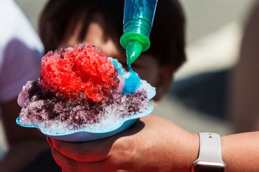 Closeup Woman Pouring Blue Syrup Onto Ice Of Snow Cone