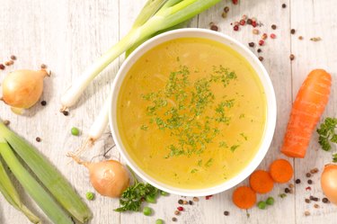 vegetable broth in bowl with veggies around it