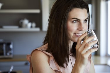 Beautiful woman in kitchen drinking a glass of water