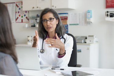 doctor wearing glasses and stethoscope talking to patient about pcos and fertility