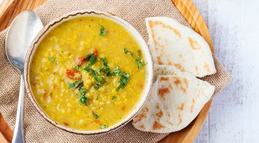 Toor dal with pita bread in a ceramic white bowl on a wooden background. Top view. Copy space