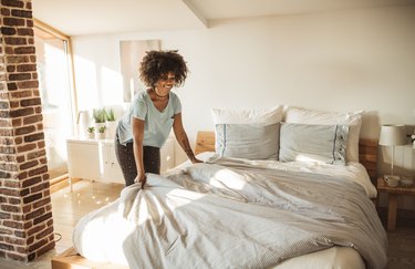 A woman changing the sheets on her bed at home