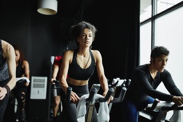 Woman riding stationary bike during fitness class in cycling studio