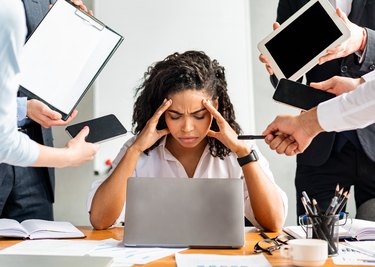 Stressed Businesswoman At Laptop Touching Head Sitting In Modern Office