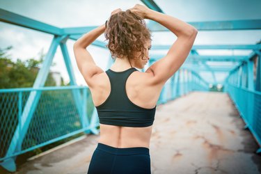 woman tying her hair in a ponytail before her workout