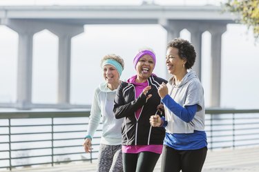 Three people power walking together on a waterfront