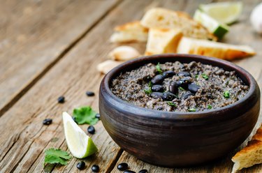 Bowl full of dried thiamin-rich black beans sits on a wooden tabletop.