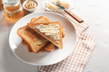 Plate with toasted bread and butter on table