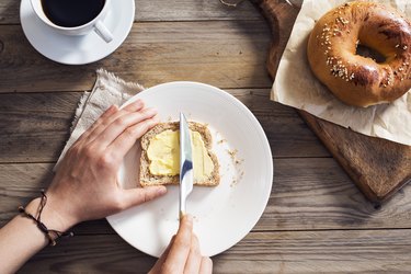 Woman hand spreading vegan butter on sliced bread