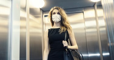 woman wearing face mask in elevator going to work