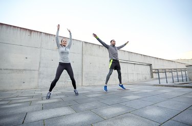 happy man and woman jumping outdoors