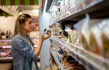 Beautiful woman at the refrigerated section of the supermarket reading label on a dairy product