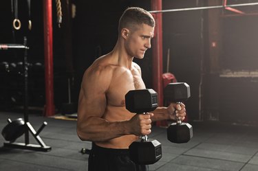 Young handsome bodybuilder during his arm workout in the gym