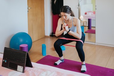 Woman performing squat with small looped resistance band