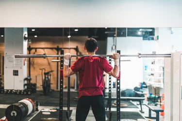 rear view of man using barbell to do a good morning exercise