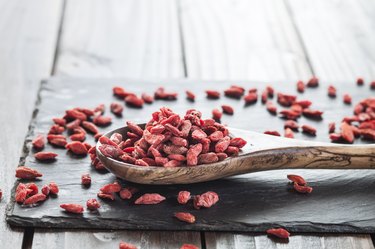 Wooden spoon with dried goji berries on a slate, superfood