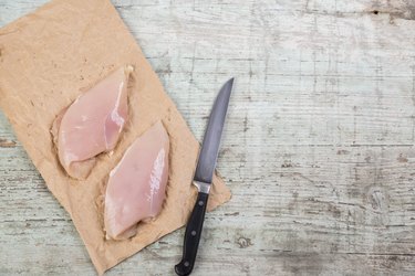 Chicken breast on brown paper and a knife