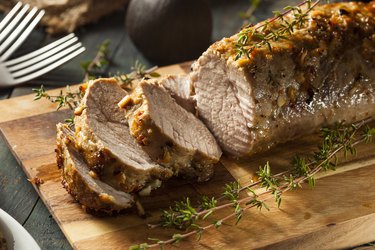 Roasted Pork Tenderloin, a food high in taurine, sliced on a wooden cutting board