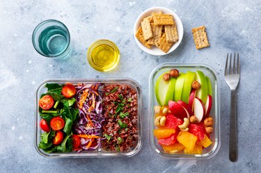 Lunch box with vegetables, brown rice and fruits salad. Healthy eating. Grey background. Top view.