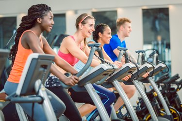 Side view of a beautiful woman smiling while cycling during exercising class at the gym