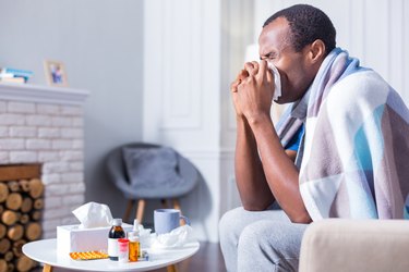 Adult man sneezing because he has the flu