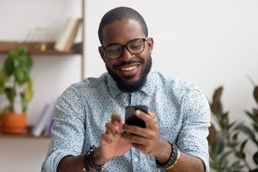 a smiling adult using mobile apps at work to laugh as a way to de-stress