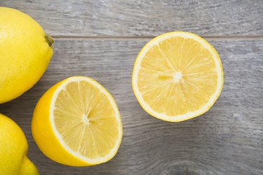 Ripe, yellow, halved lemon fruit on wooden texture table. Directly above view.